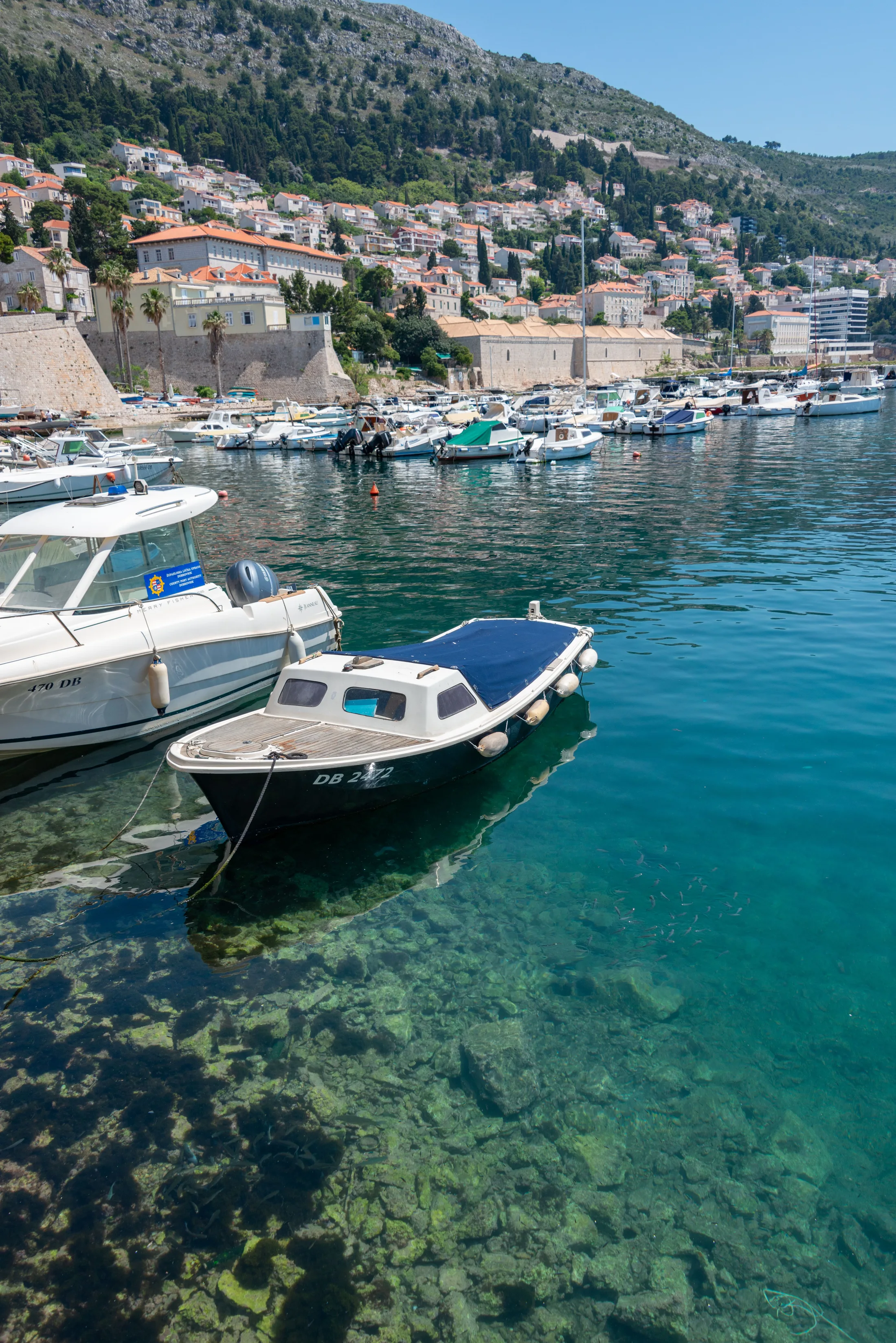 Boats moored below stone walls in Dubrovnik harbour
